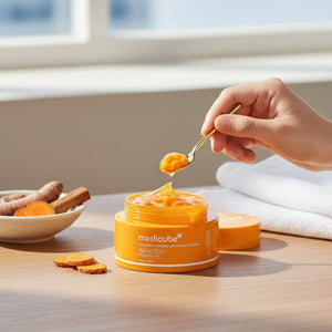 Crema hidratante KSTANDARBEAUTY Medicube con cápsulas de cúrcuma y ácido kójico, textura gel naranja sobre cuchara